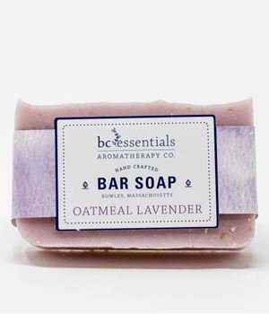A handmade lavender oatmeal bar soap from BC Essentials, labeled on a purple and white label, wrapped in lavender paper against a white background.