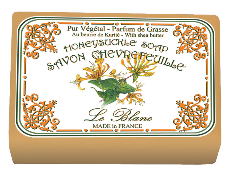 An ornate label on a bar of Le Blanc Made in France soap featuring decorative orange and green floral patterns and text that reads "Le Blanc Honeysuckle Wrapped Soap, made in France.