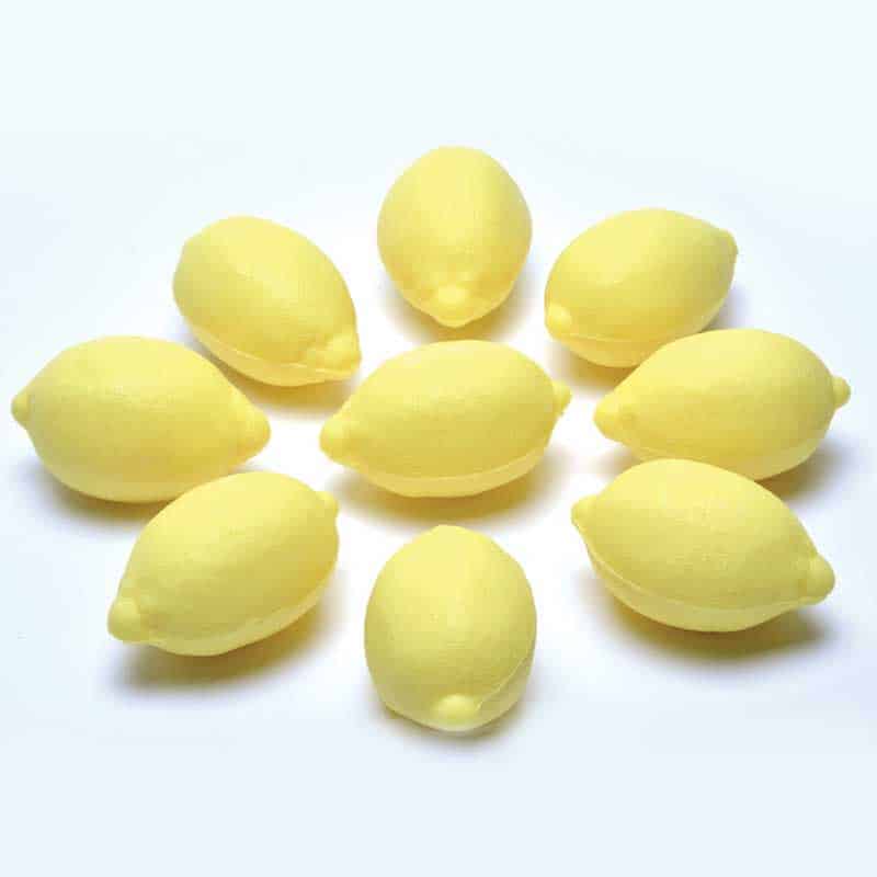 A group of yellow, La Lavande Lemon Shaped French Soaps neatly arranged on a white background.