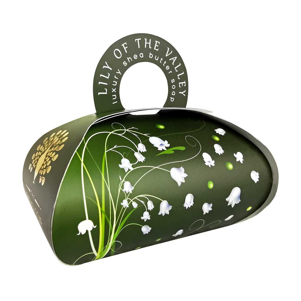 An elegant, green and white floral-patterned cosmetic tin with a half-circle handle on top, labeled "The English Soap Co. Lily of the Valley Large Gift Soap." The design includes stylized white lily flowers.