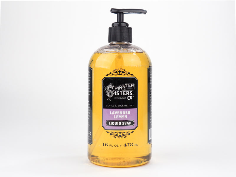 A large transparent bottle of Spinster Sisters Co. lavender lemon liquid soap featuring a black and yellow label, enhanced with babassu seed oil, displayed against a plain white background.