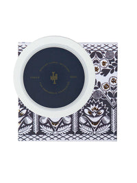A round container with a navy lid, featuring elegant golden accents and text, placed on a navy and white floral patterned box, contains Margot Elena's Lollia Dream Body Butter.