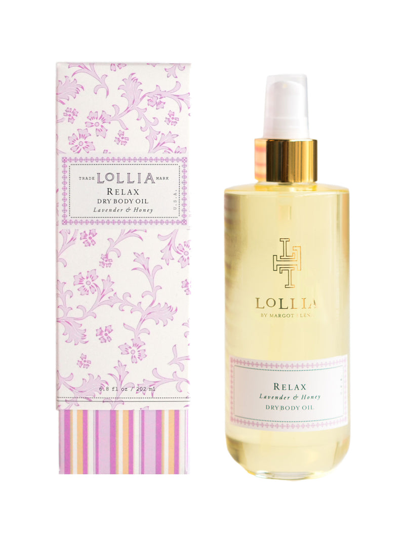 A bottle of Lollia Relax Dry Oil Body by Margot Elena with lavender, honey, and sweet almond oils next to its decorative pink and white striped packaging with floral designs.