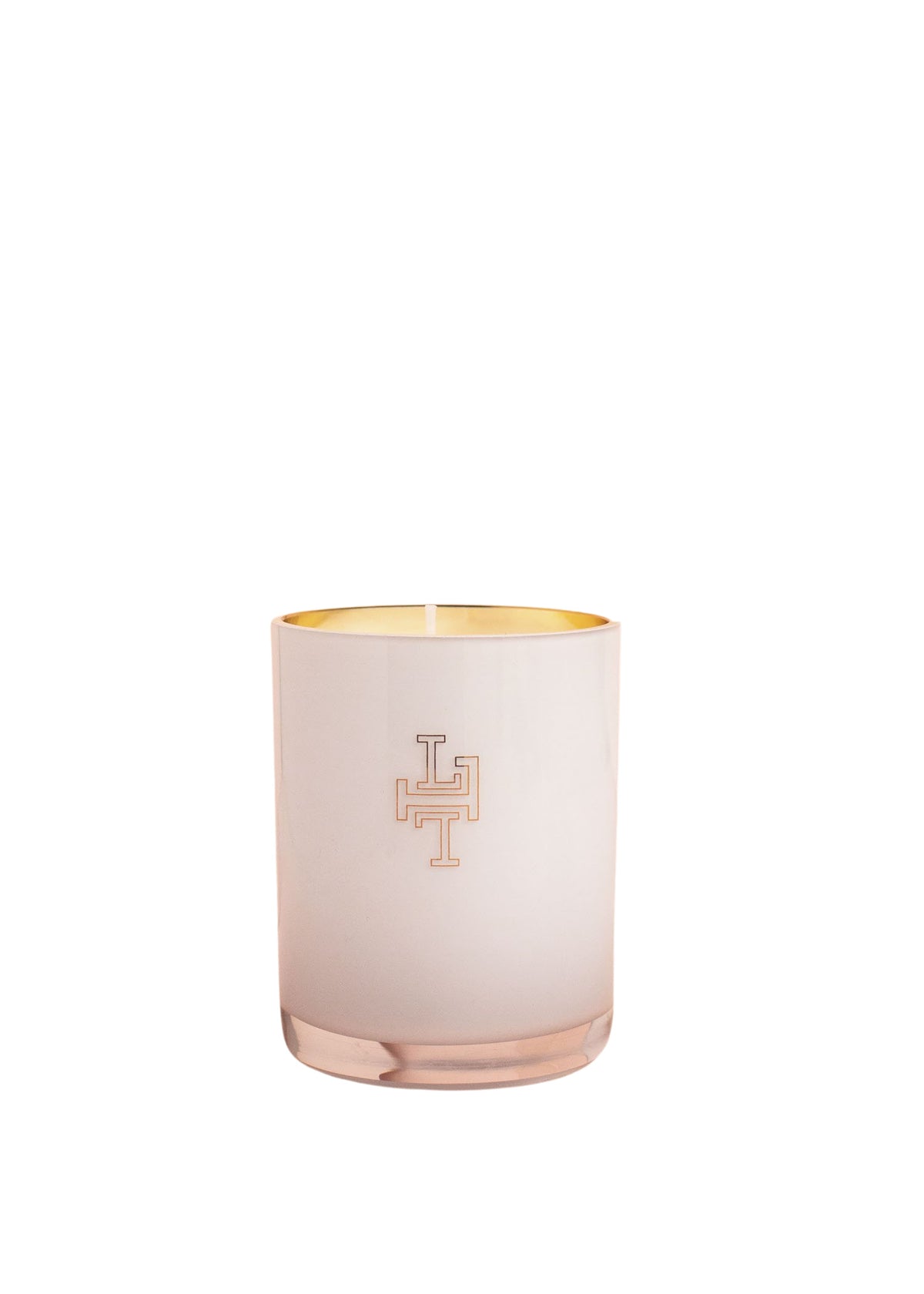 A pink-tinted cylindrical handblown glass candle holder with a white, cross-like emblem on the front and gold interior, against a white background for the Lollia Wish No. 22 Luminary Candle by Margot Elena.