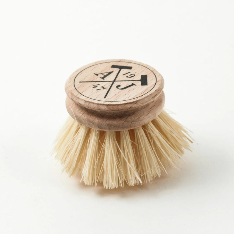 A compostable wooden Andrée Jardin Tradition Handled dish brush with a circular top engraved with Japanese characters, set against a white background.
