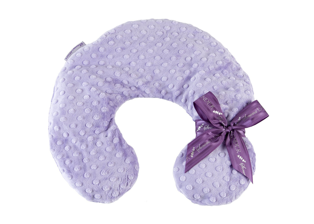 A soft, Sonoma Lavender - Lavender Dot Neck Pillow neck pillow with raised dot texture, adorned with a decorative satin bow, on a white background.