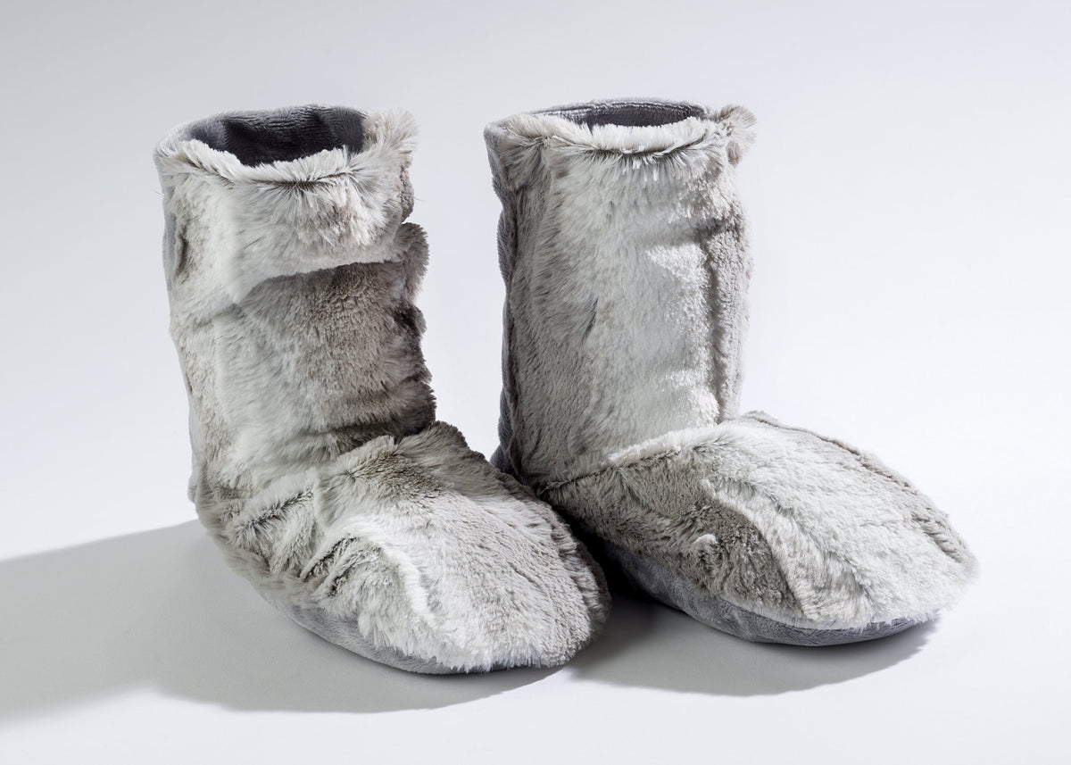 A pair of Sonoma Lavender Angora Platinum Spa Booties standing on a white surface, highlighted by natural light casting soft shadows.