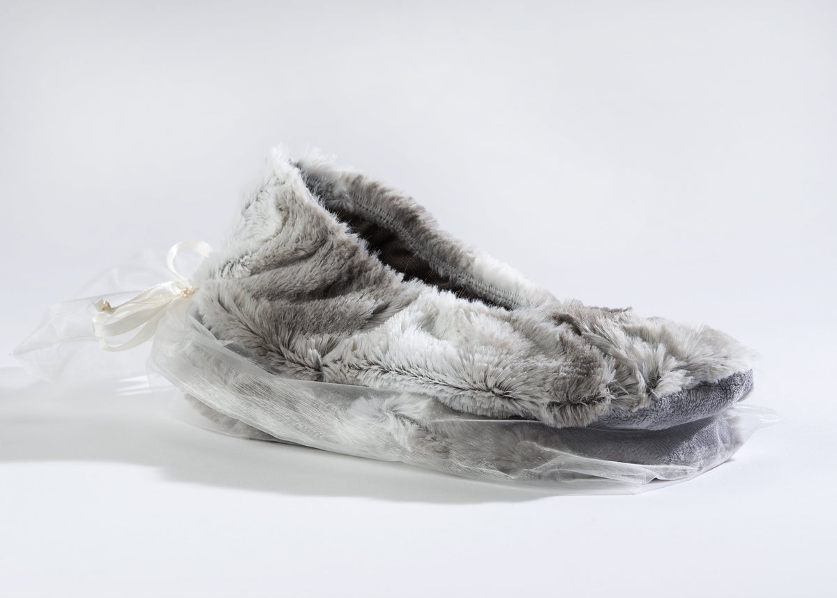 A pair of Sonoma Lavender Angora Platinum Heatable Footies with flaxseed inserts, wrapped in a clear plastic bag, tied with a white ribbon, set against a plain white background.