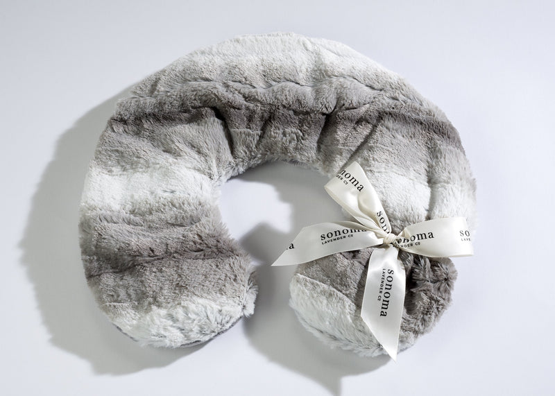 A plush Sonoma Lavender Angora Platinum neck pillow with a white ribbon labeled "Sonoma Lavender" tied around it, displayed on a light, textured background.