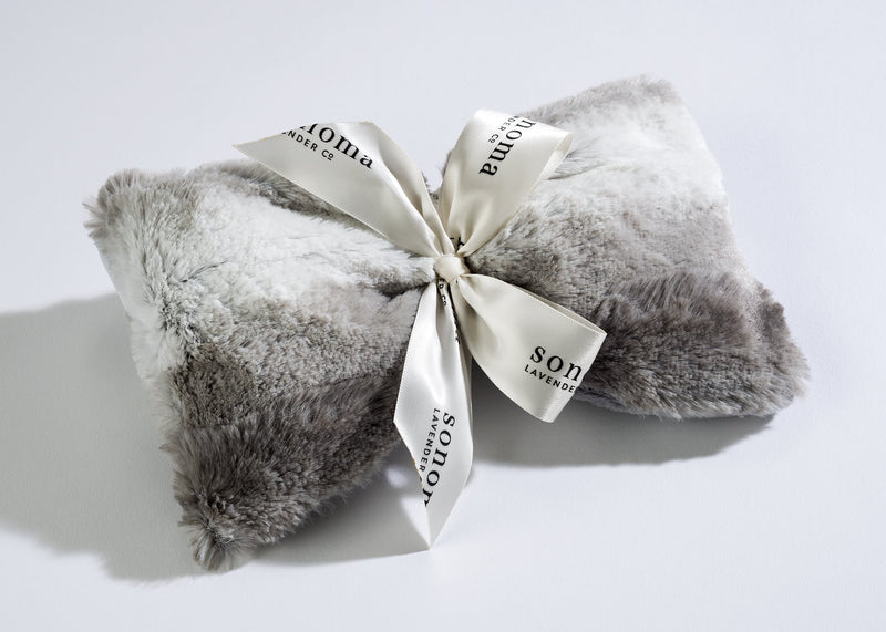 A luxurious grey and white Sonoma Lavender Angora Platinum Spa Mask, folded and tied with an elegant white ribbon featuring the text "sons + daughters" in stylized script, set against a clean, light background.