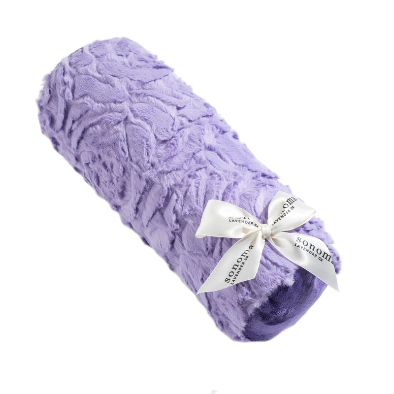A soft, purple Sonoma Lavender Bellflower Rose faux fur heated neck roll tied with a white ribbon that has text on it, isolated on a white background.