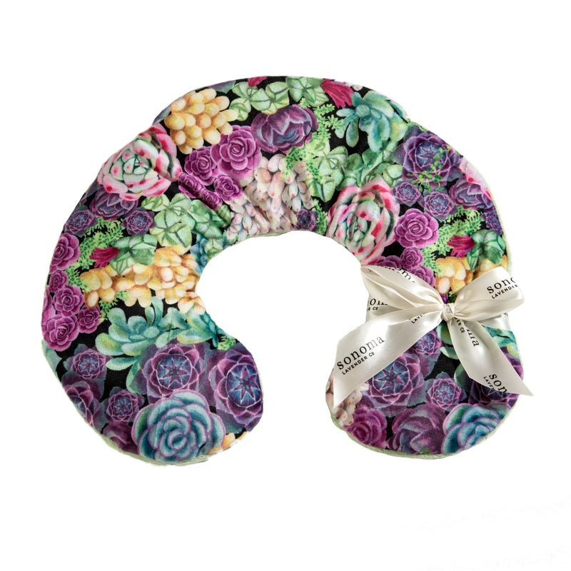 A Sonoma Lavender Succulents neck pillow with vibrant colors and a variety of flowers, featuring a satin ribbon with the text "sonoma" tied on one end and infused with lavender aromatherapy.