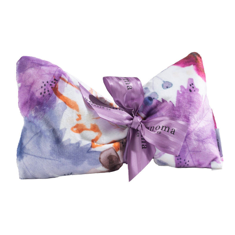 A colorful headband with a large bow, featuring a Sonoma Lavender Autumn Splendor Spa Mask print and a tied ribbon with the text "ban.do" in the center.