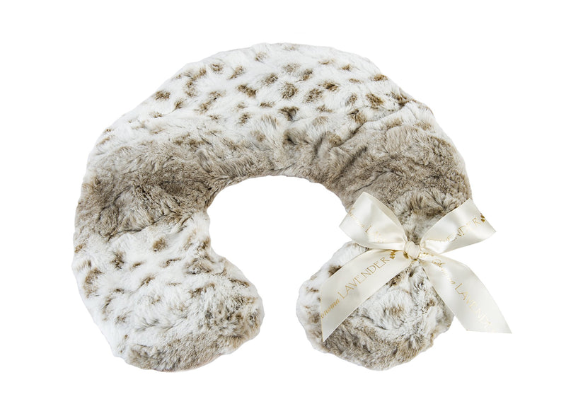 A plush, faux fur Sonoma Lavender Arctic Circle neck pillow in a light gray color with darker gray spots, featuring a decorative cream-colored ribbon with the text "lavender" printed on it, isolated on a white background.