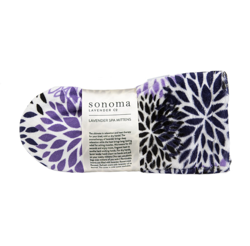 A Sonoma Lavender Purple Bloom spa mittens with a floral pattern and a label describing the product features, including heat therapy and lavender aromatherapy.