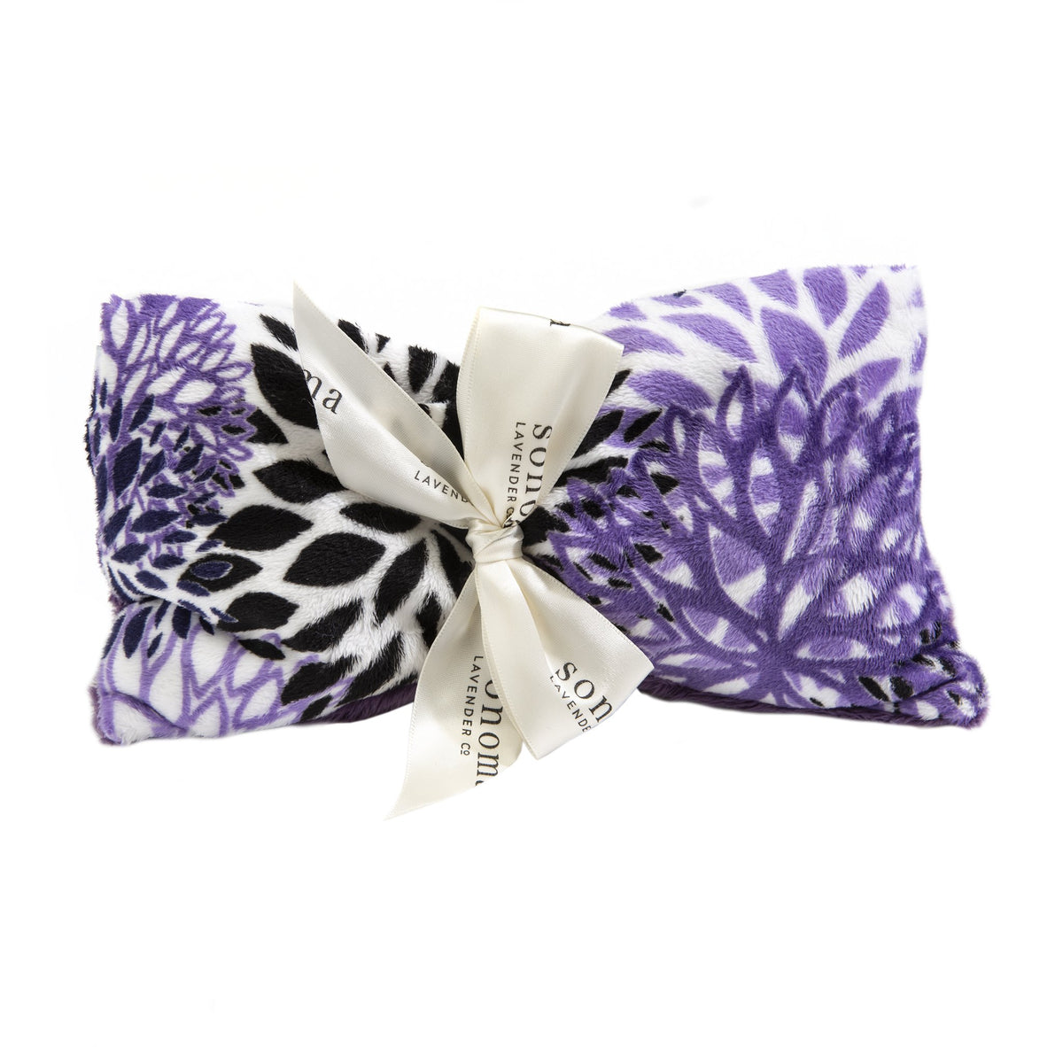 A Sonoma Lavender Purple Bloom spa mask featuring a purple and white floral pattern, adorned with a cream ribbon tied in a bow, labeled "saje wellness lavender relaxation.