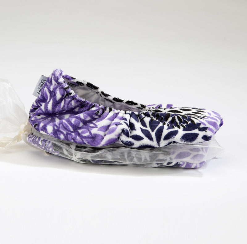 A pair of Sonoma Lavender Purple Bloom Heatable Footies with flaxseed inserts displayed on a white background, packaged partially in a clear plastic bag.