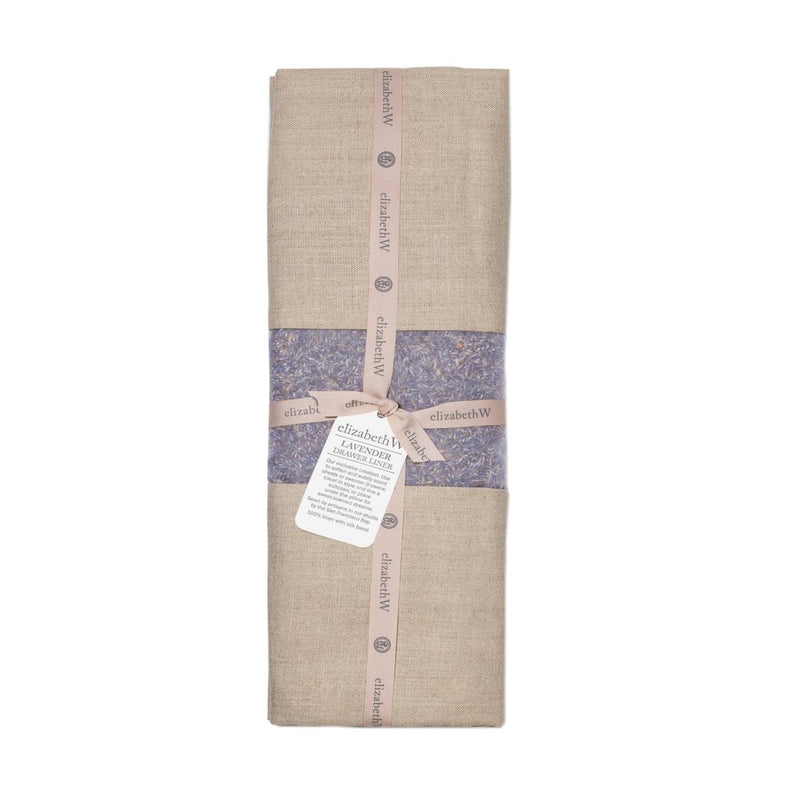 A Elizabeth W lavender linen heat wrap packaged with printed Elizabeth W brand ribbons and a hanging product tag, displaying detailed product information. The wrap is neutral colored with light purple detailing and infused with French lavender.