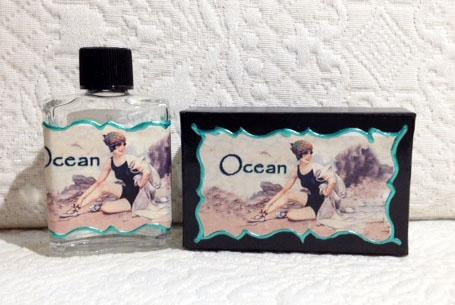 A Seventh Muse Fragrant Oil - Ocean bottle and a soap bar with matching labels featuring an illustrated image of a person at a beach with the words "Clean Ocean air" printed on them.