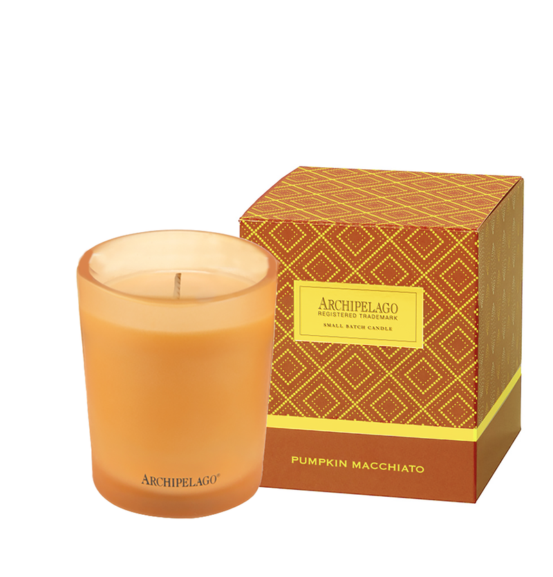 A scented candle in a glass holder beside its packaging box labeled "Archipelago Botanicals, Pumpkin Macchiato, Cardamom Vanilla Spice Candle.