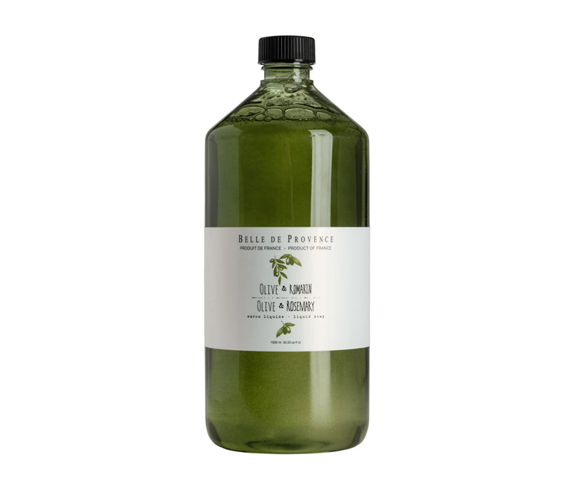 A large transparent glass bottle containing green Belle de Provence Olive Liquid Soap Refill with Rosemary labeled "Lothantique, olive & rosemary" with a black cap, isolated on a white background.