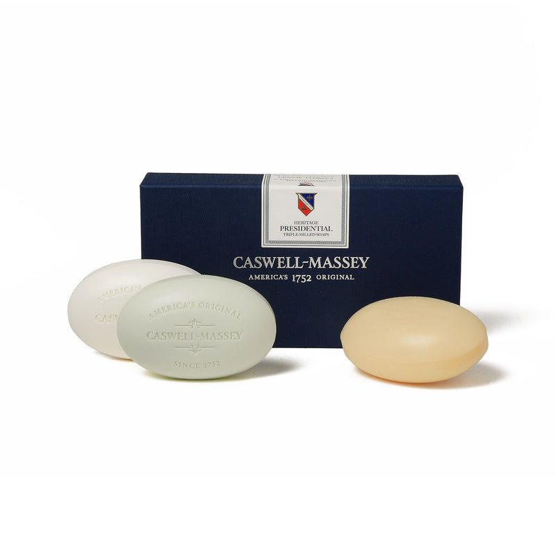 Three oval-shaped, triple-milled soaps in front of a dark blue box labeled "Caswell - Massey Heritage Presidential Three-Soap Set, America's Original, since 1752" on a white background.
