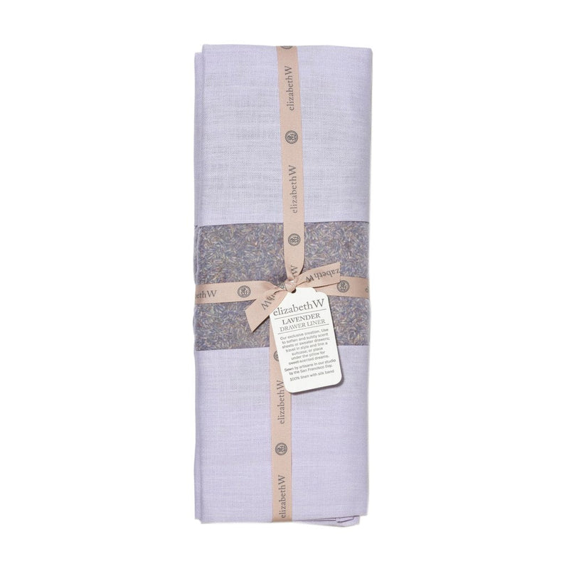A neatly folded lavender-colored linen napkin secured with two floral-patterned paper bands, labeled "elizabeth W Lavender Linen Drawer Liner - Purple" with an attached description tag.