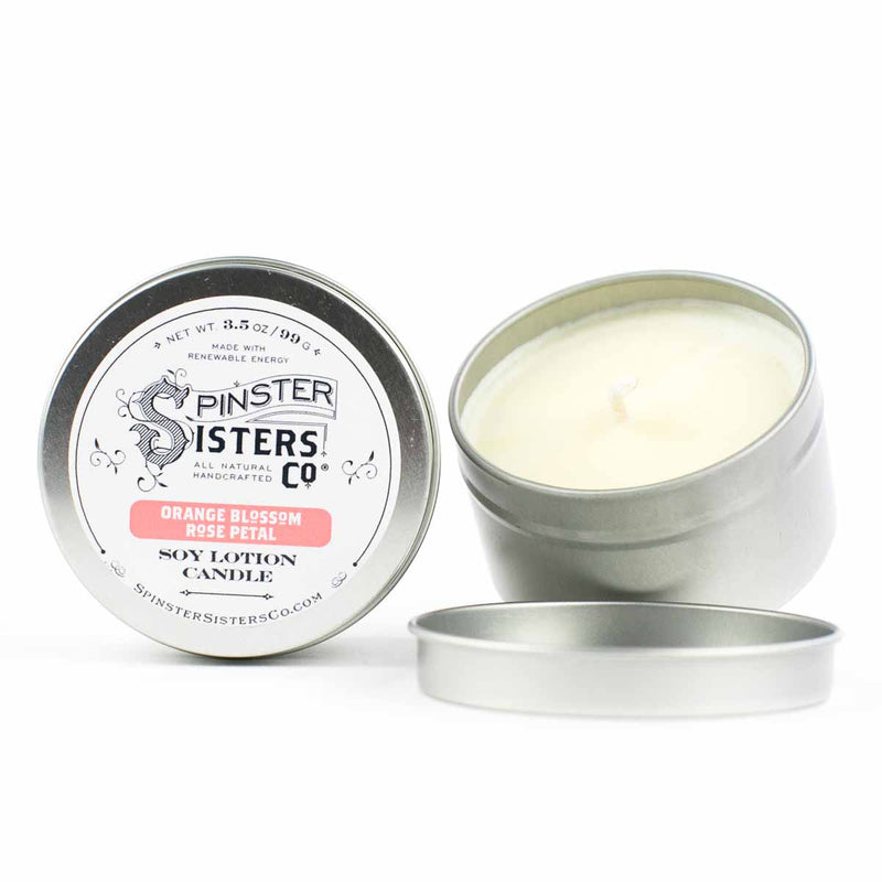 A Spinster Sisters Soy Lotion Candle - Orange Blossom & Rose Petal, scented with orange blossom & rose petal and infused with fair-trade cocoa and shea butters. The open tin reveals the creamy white candle, positioned by Spinster Sisters, Co.