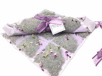 Nine sachets of Sonoma Lavender Liner, organized in a grid and tied with purple ribbons, each bearing a label with hand-written text, encased in embroidered lavender fabric, against a white background.