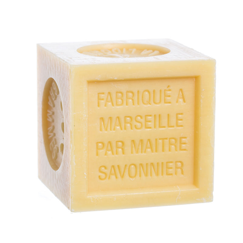 A cube-shaped, yellow French Soaps Savon de Marseille with Crushed Flowers - Honey with carved text "fabriqué à Marseille par maître savonnier" on one side and "savon de Marseille" on another, isolated on a white