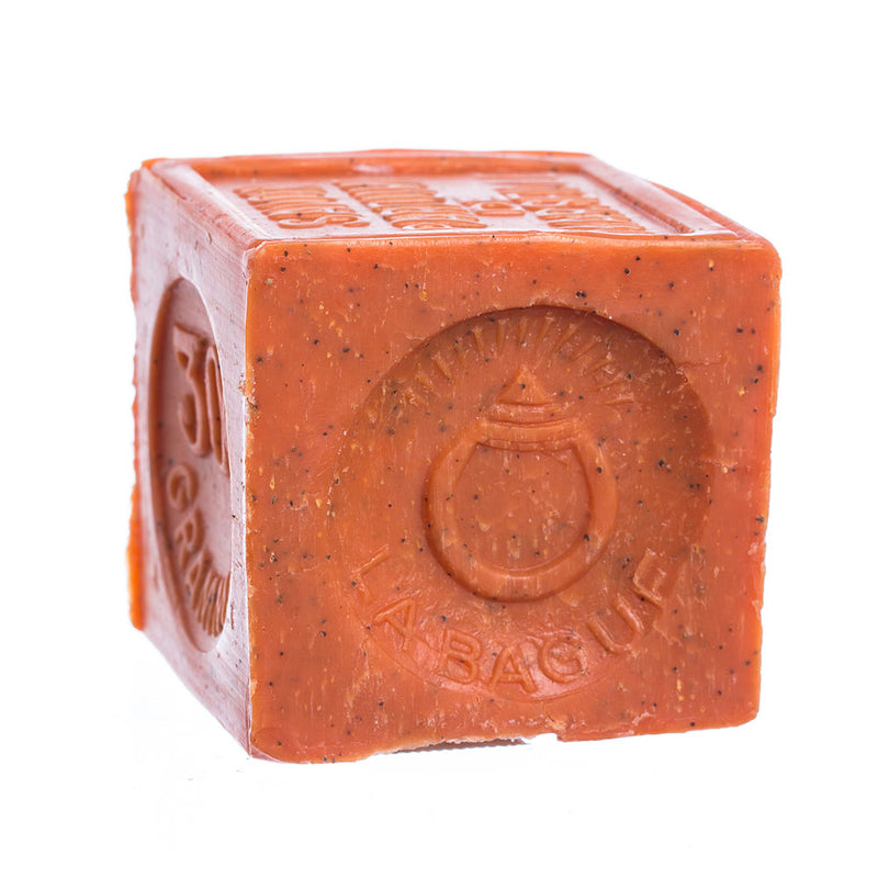 A cube-shaped, orange-red colored bar of French Soaps Savon de Marseille with Crushed Flowers - Orange, with embossed text and designs on its visible sides, isolated on a white background, infused with a fresh oranges fragrance.