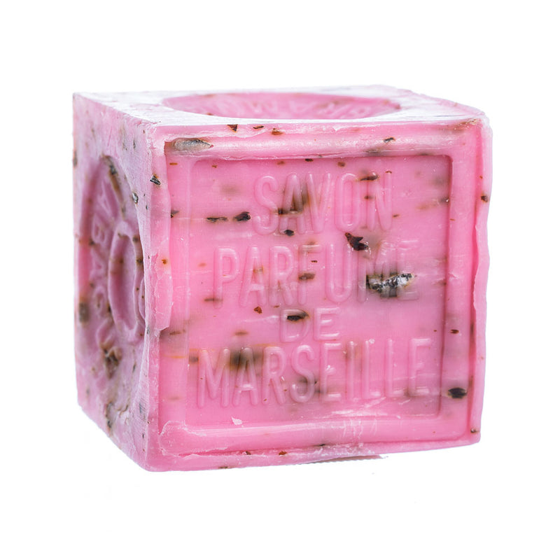 A pink cube-shaped French Soaps Savon de Marseille with Crushed Flowers - Rose soap, with visible text "savon de Marseille" imprinted on its surface, isolated on a white background.