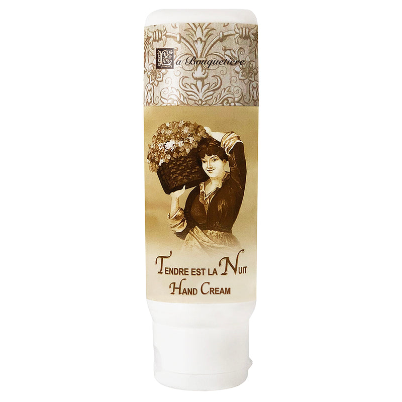 A tube of La Bouquetiere Tendre est la Nuit hand cream featuring vintage-style artwork of a woman holding a basket of flowers, with elegant decorative motifs and infused with Organic Shea Butter.