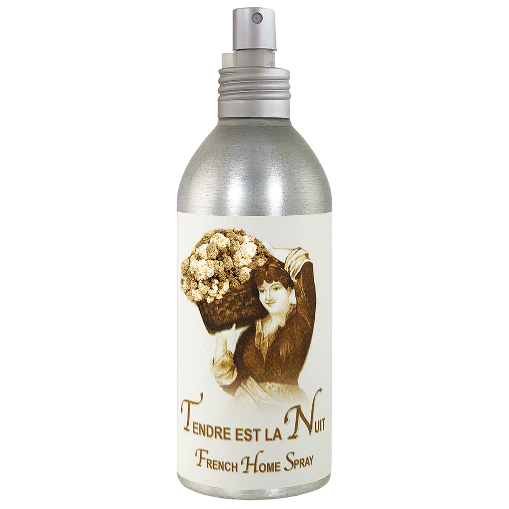 A vintage style spray bottle labeled "La Bouquetiere Tendre est la Nuit French Home Spray," featuring an image of a woman smiling and holding a bouquet. The bottle is silver with a spray nozzle.