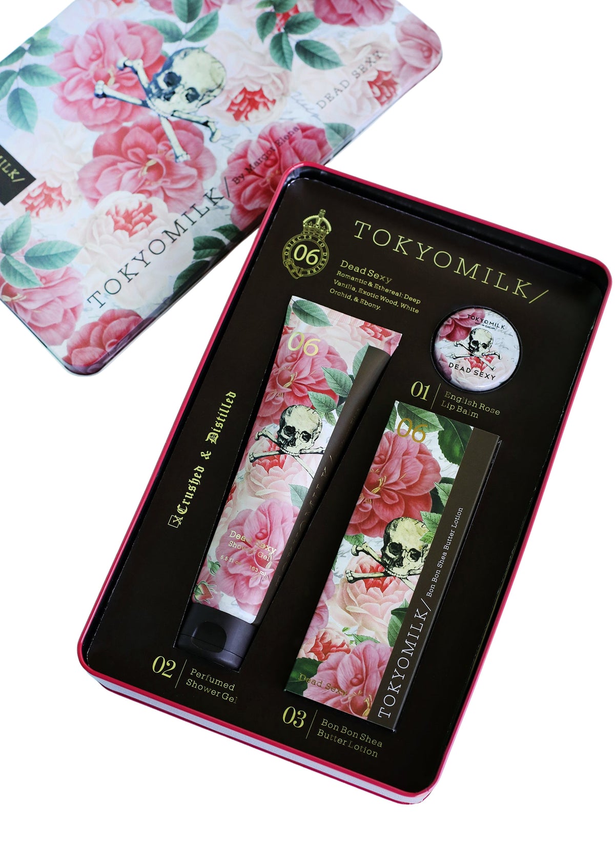 A Margot Elena TokyoMilk Dead Sexy Gift Set Tin displayed in an open tin box, featuring a floral and skull print design. The set includes a shea butter handcreme, lip balm, and e