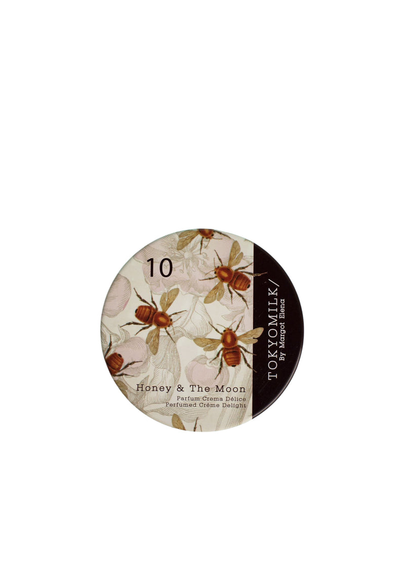 A round token featuring a floral design with the text "10," "Margot Elena," and "TokyoMilk Honey & The Moon No. 10 Parfum Crema" on a cream background.