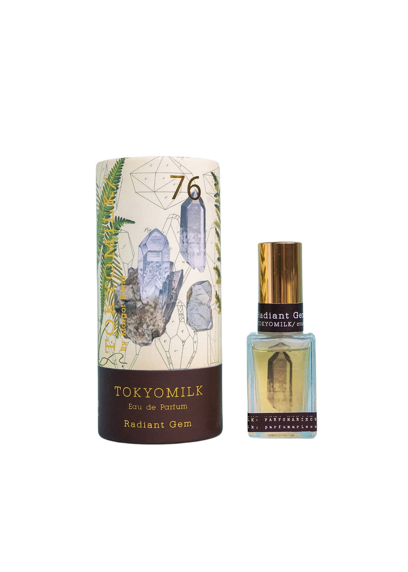 A bottle of Margot Elena TokyoMilk Radiant Gem No. 76 Parfum and its packaging featuring illustrations of crystals, winter daphne, and plants on a white background.