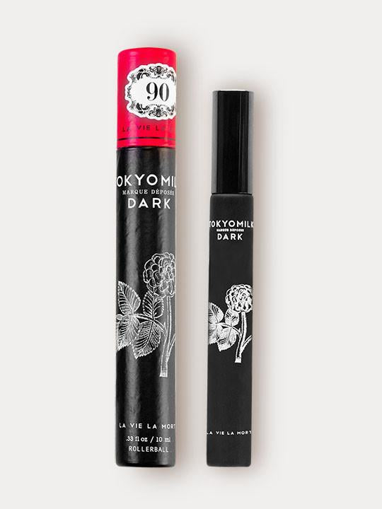 Two TokyoMilk Dark La vie La Mort No.90 rollerballs against a white background: one is labeled "Madara Rose" with a red cap and floral design; the other, named "White Tuberose".