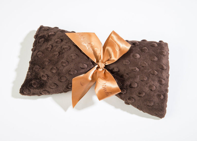 A luxurious Sonoma Timber Lake Sedona Brown Dot heated spa mask tied with a shiny gold satin ribbon bow, photographed on a white background by Sonoma Lavender.