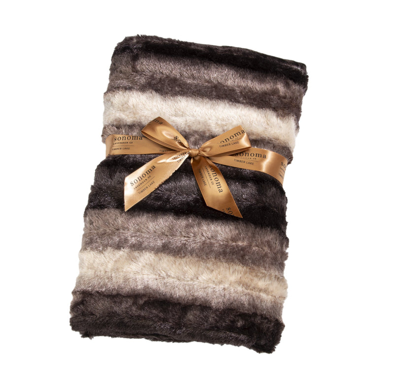 A plush striped Sonoma Timber Lake Chinchilla Spa Blankie in shades of brown and cream, neatly rolled and tied with a golden ribbon featuring the text "aromatic SPA BLANKIE" repeated along its length. Brand Name: Sonoma Lavender