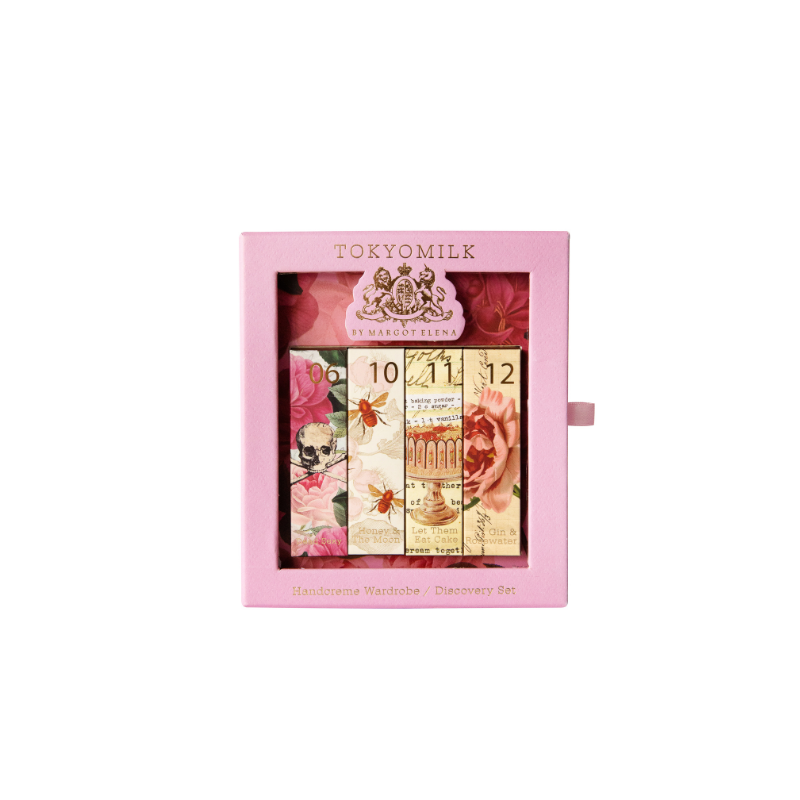 A Margot Elena TokyoMilk Handcreme Wardrobe discovery set, featuring a pink book-style case open to display four floral-themed handcreme bottles arranged next to a decorative clock image.
