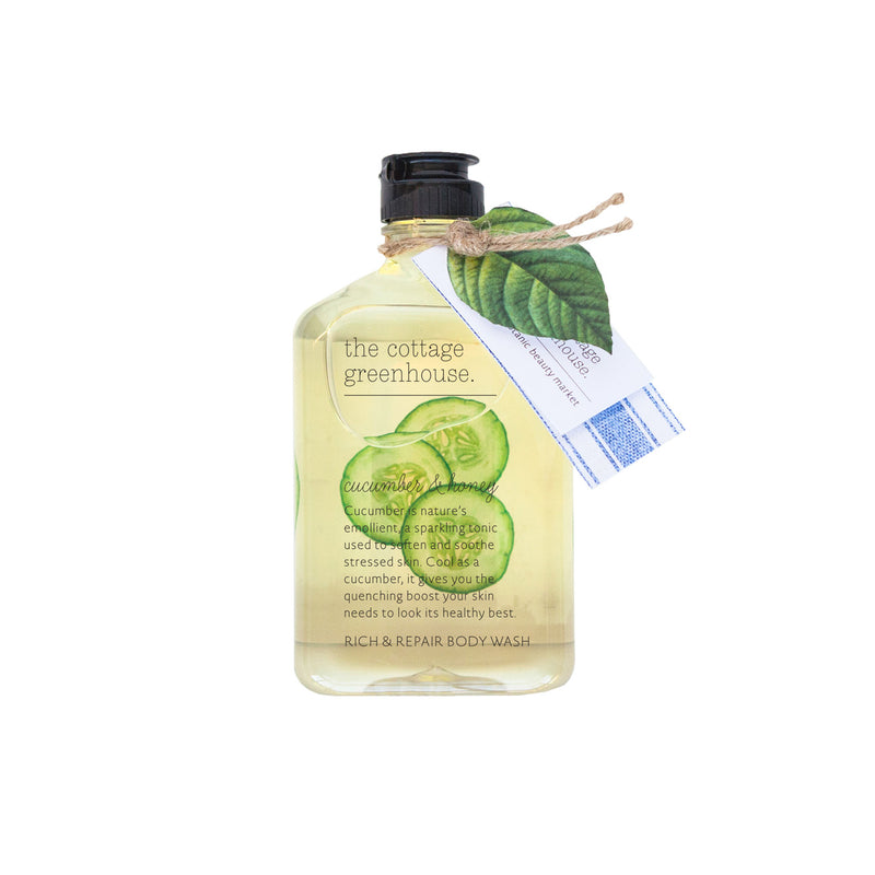 Transparent bottle of The Cottage Greenhouse Cucumber & Honey Body Wash with a leaf and a tag wrapped around its neck, isolated on a white background by Margot Elena.