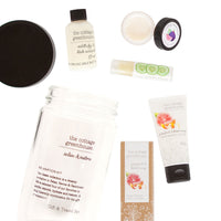 A collection of personal care products from Margot Elena, including The Cottage Greenhouse Fruit Relaxation Kit, bubbling milk bath, hand cream, and nourishing lip repair, arranged on a white background.