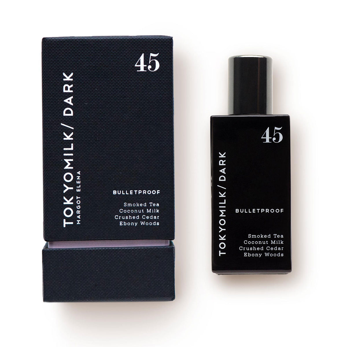 A bottle of Margot Elena's TokyoMilk Dark Bulletproof No. 45 Eau de Parfum next to its packaging box. The bottle and box are black, with white text listing the fragrance notes: smoked tea, coconut.