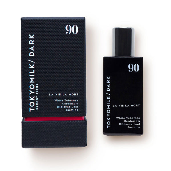 A Margot Elena TokyoMilk Dark La Vie La Mort No. 90 Eau de Parfum bottle labeled "la vie la mort" next to its packaging, featuring floral fragrance notes of white tuberose, cardamom, hibiscus leaf.