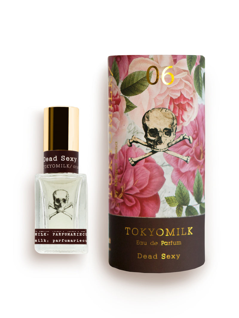 Two perfume bottles on a white background: a small glass bottle labeled "TokyoMilk Dead Sexy No. 6 Parfum" with a skull and bones design, featuring deep vanilla notes, and a larger cylinder with a floral and skull print, from Margot Elena.