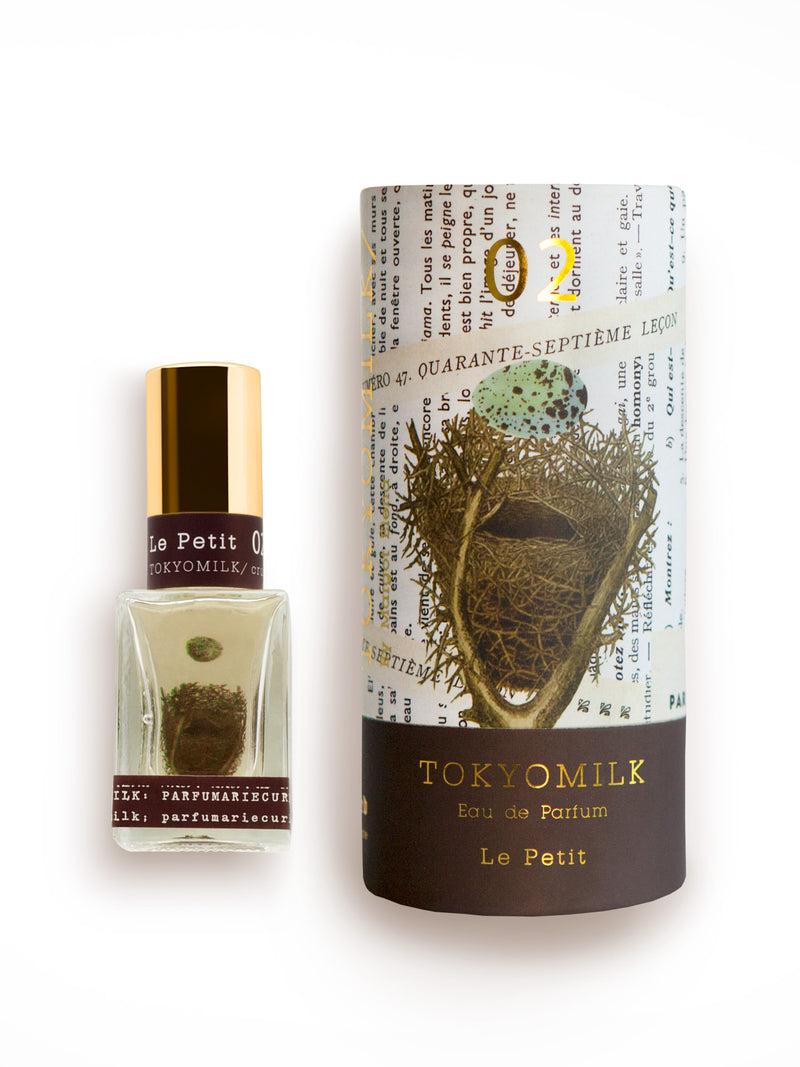 A bottle of Margot Elena's TokyoMilk Le Petit No. 2 Parfum next to its cylindrical packaging decorated with vintage map designs and a peony graphic.