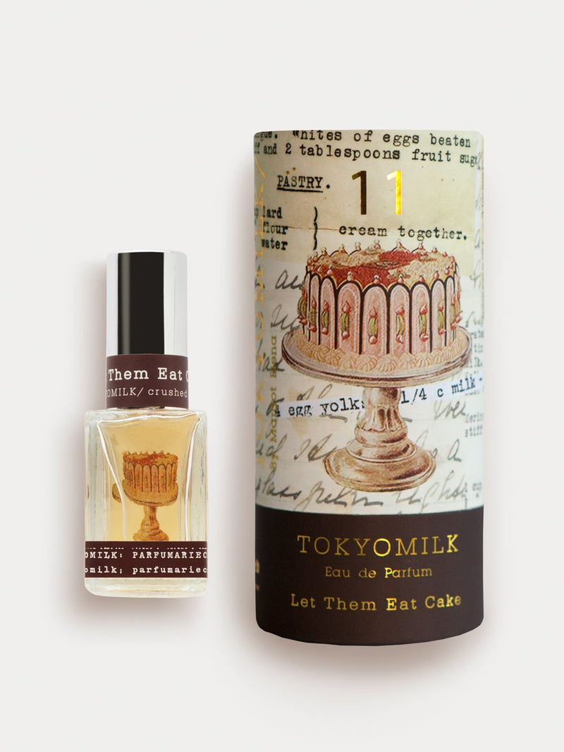 A bottle of "Margot Elena TokyoMilk Let Them Eat Cake No. 11 Parfum" featuring a vintage-style cake illustration on an aged script background, next to a smaller.