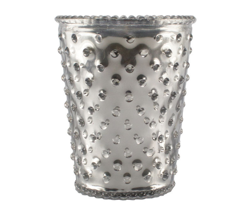 A silver, hammered metal Simpatico NO. 53 Limited Edition Vanilla Bean Metallic Hobnail Glass Candle with a dotted design and scalloped edges, isolated on a white background.