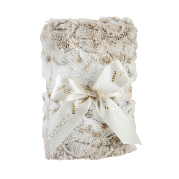 A plush, folded Sonoma Lavender Arctic Circle Heat Wrap tied with an elegant ivory ribbon printed with the words "lavender flowers" and "chamomile" in gold script, isolated on a white background.